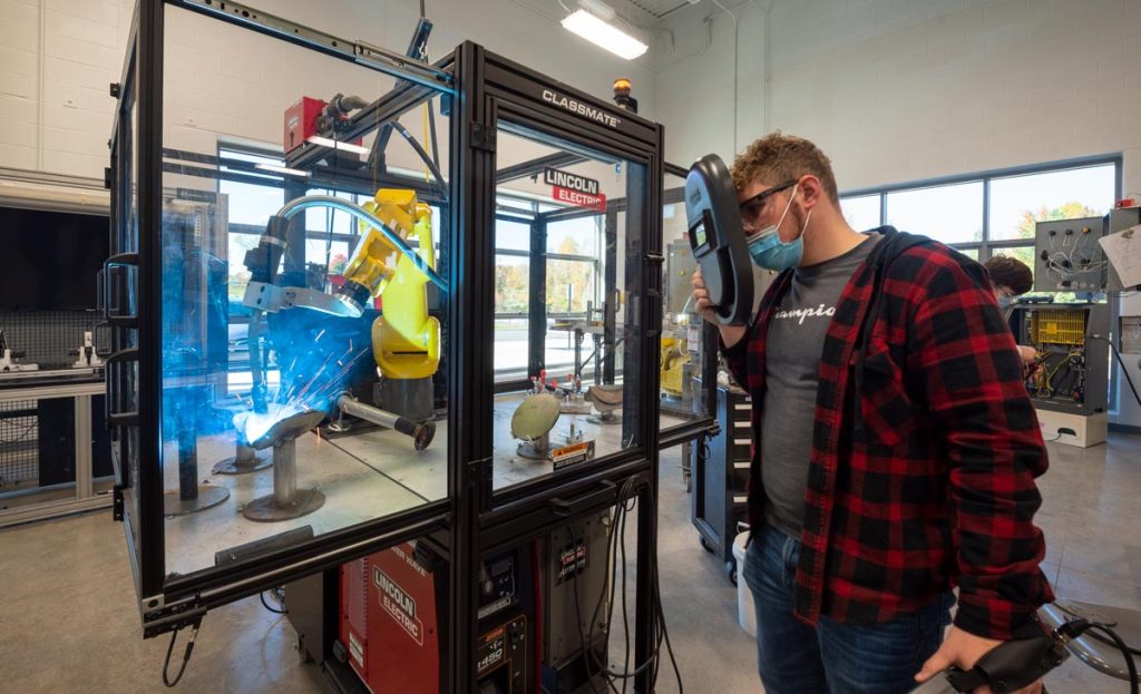 A high school student at the Lake Cumberland Regional College and Workforce Center operating a robotic welder.
