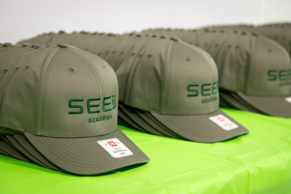 Rows of caps with SEED Academy logo on the frim